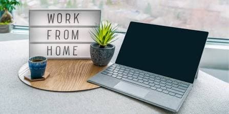 A clean, ergonomic home office desk setup with a laptop, monitor, and keyboard, illustrating a remote work or modified schedule accommodation approved with a physician's documentation.